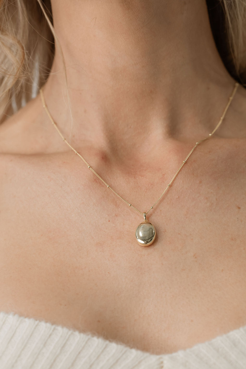model wearing bead chain necklace with gold oval pendant