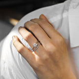 White gold round solitaire engagement ring with diamond wedding ring on a woman with a white shirt