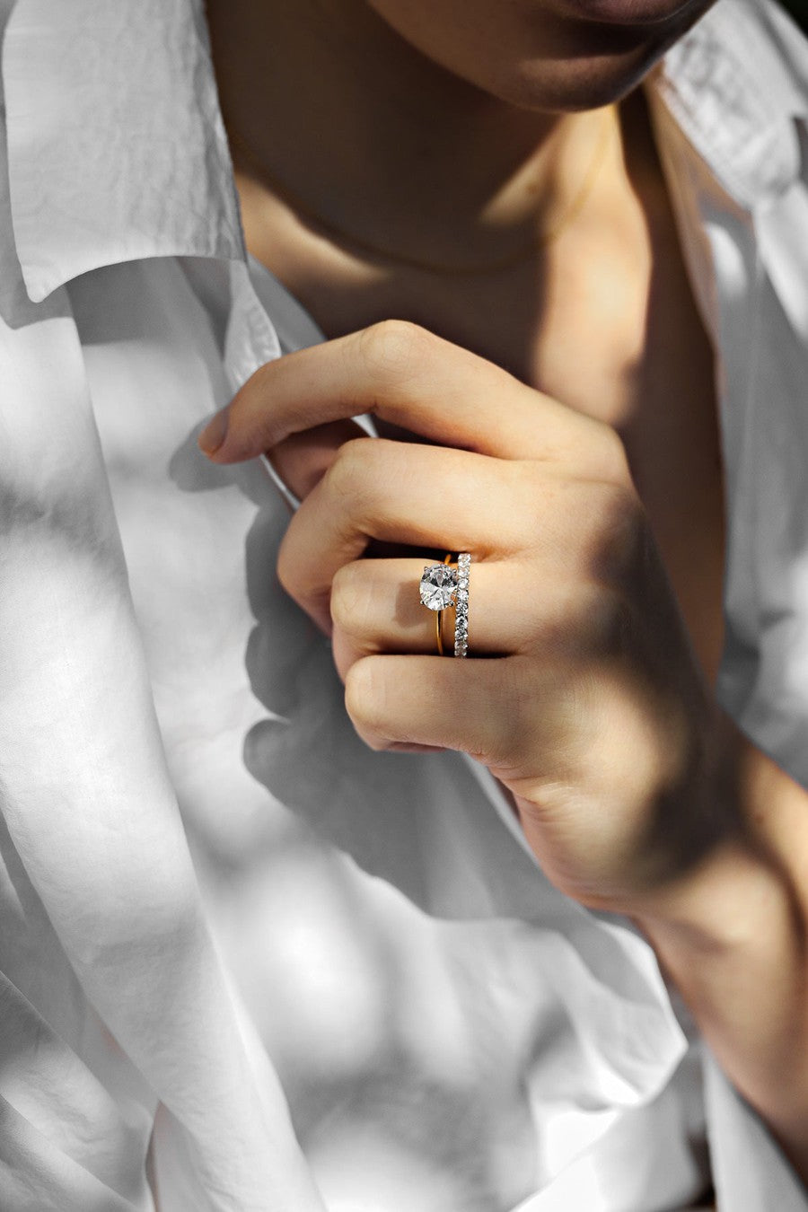 side set oval engagement ring with diamond wedding ring on a woman with a white shirt