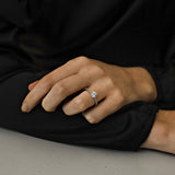 white gold diamond engagement ring with round centre diamond with 4 claws and diamonds claw set in the band on a woman wearing black