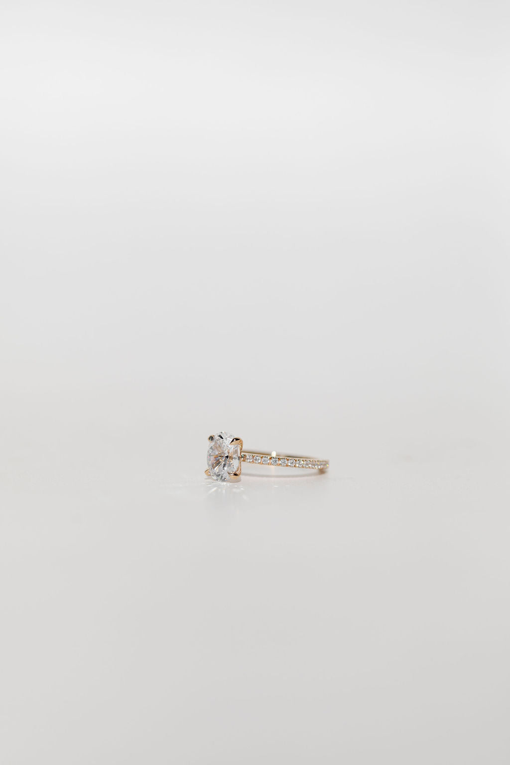 oval diamond cut engagement ring with pave set diamond band in yellow gold