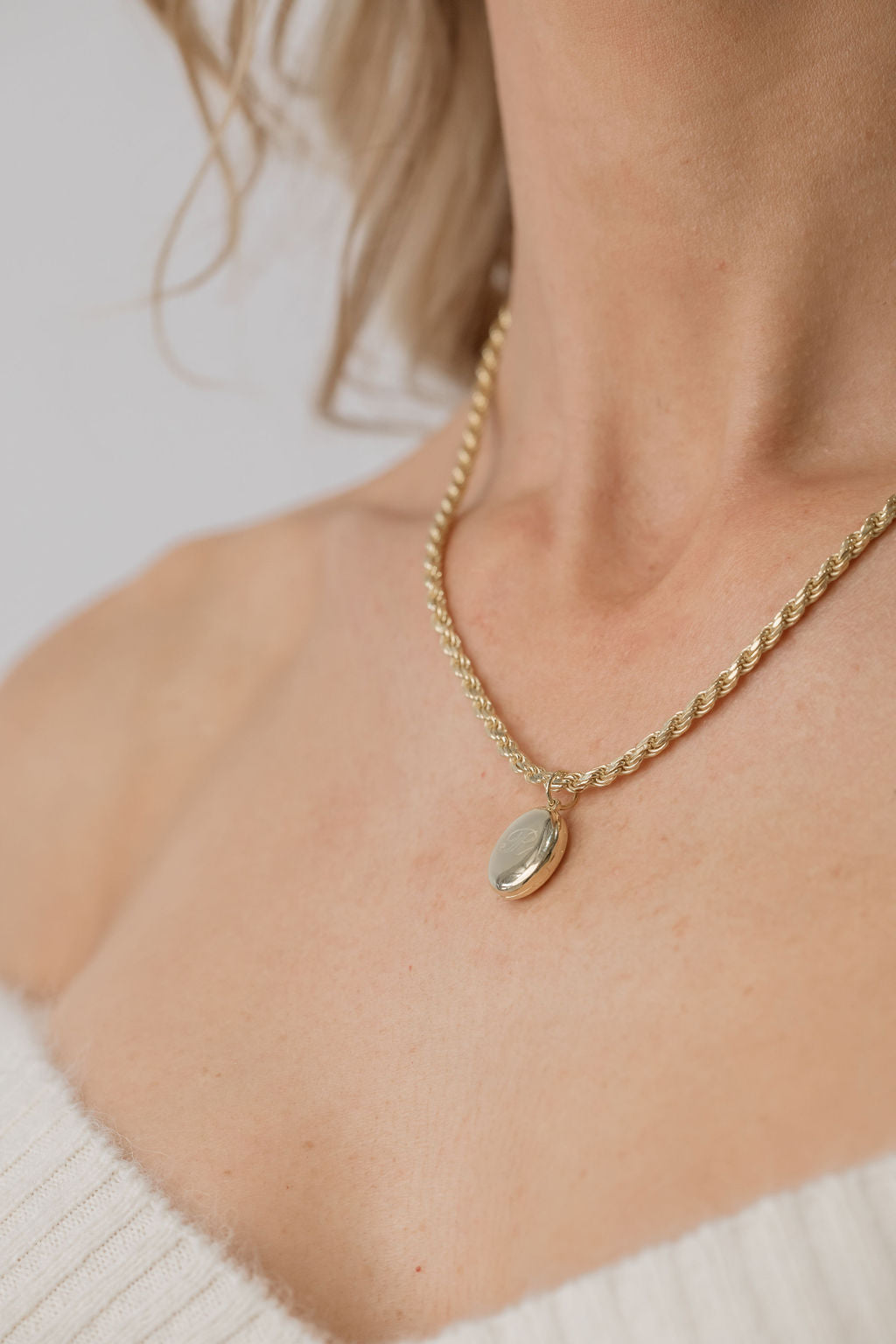 model wearing gold oval locket with rope chain necklace