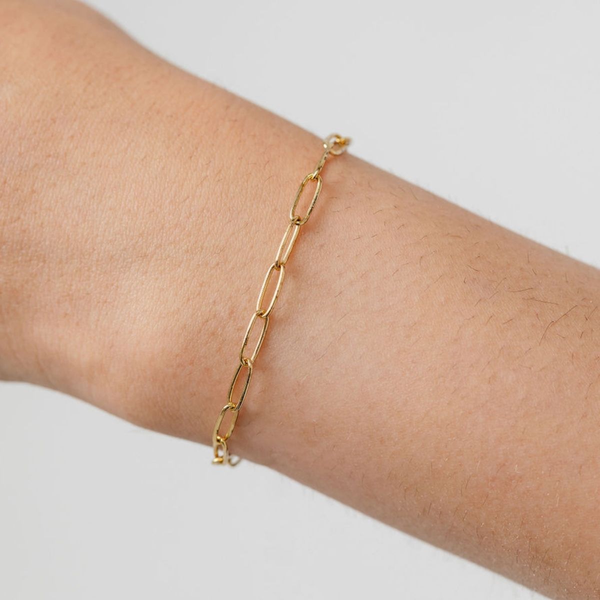 Gold paperclip chain bracelet worn on wrist showcasing modern minimalist design for everyday wear