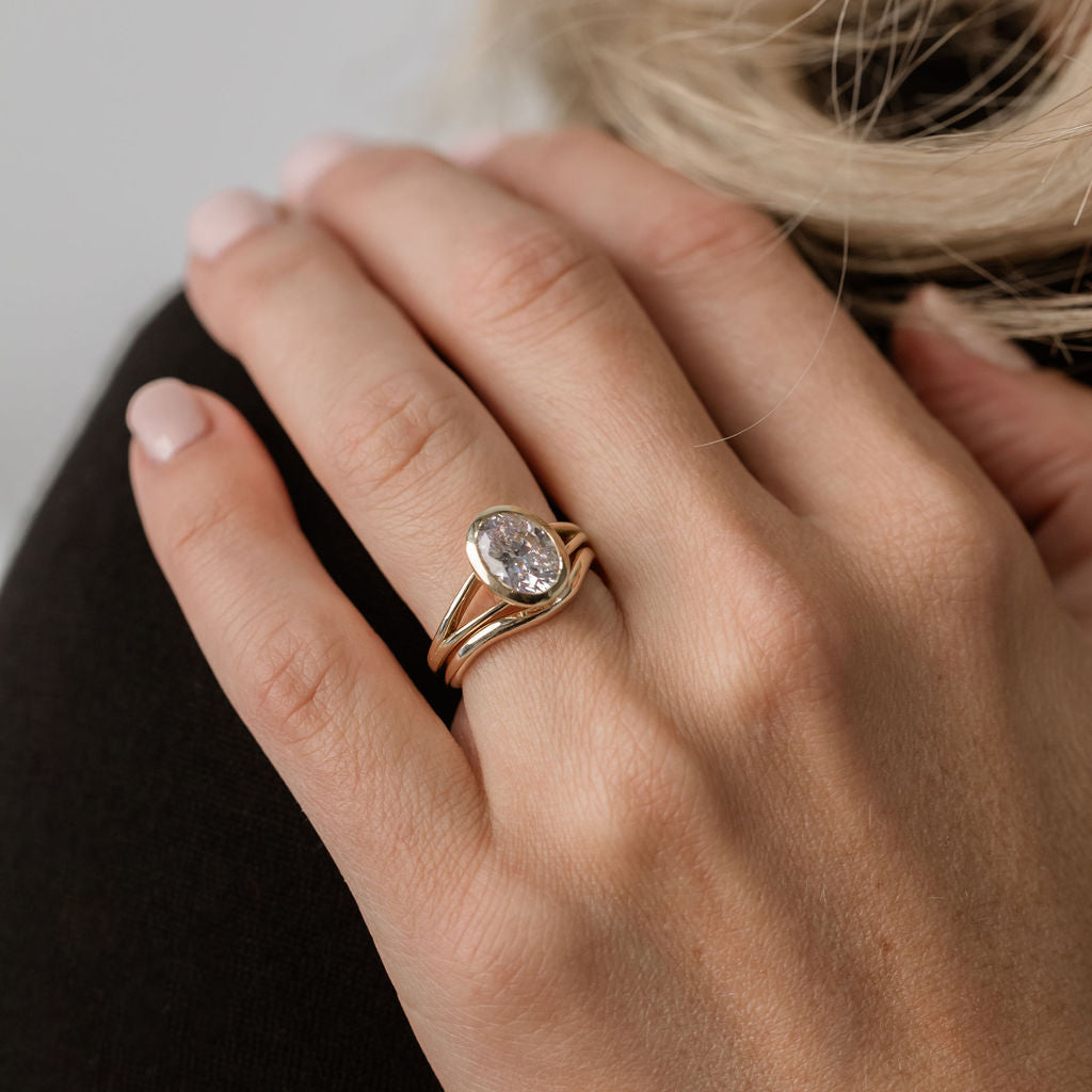 oval bevel set engagement ring with curved gold wedding ring