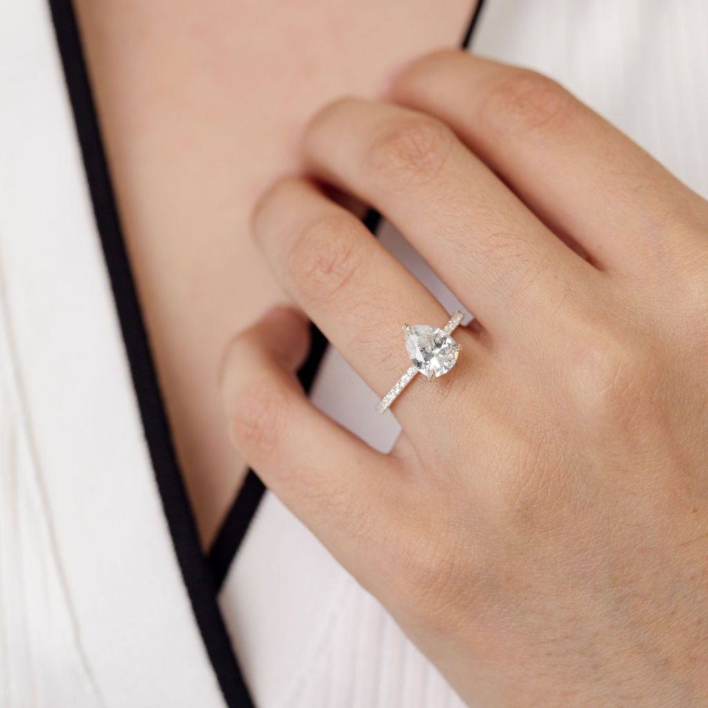 Pear cut diamond engagement ring with diamonds on the band