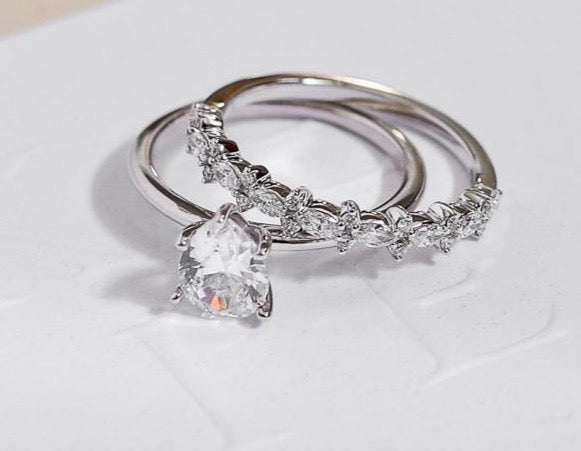 white gold diamond wedding ring with marquise diamonds and round diamonds and white gold engagement ring with pear solitaire diamond