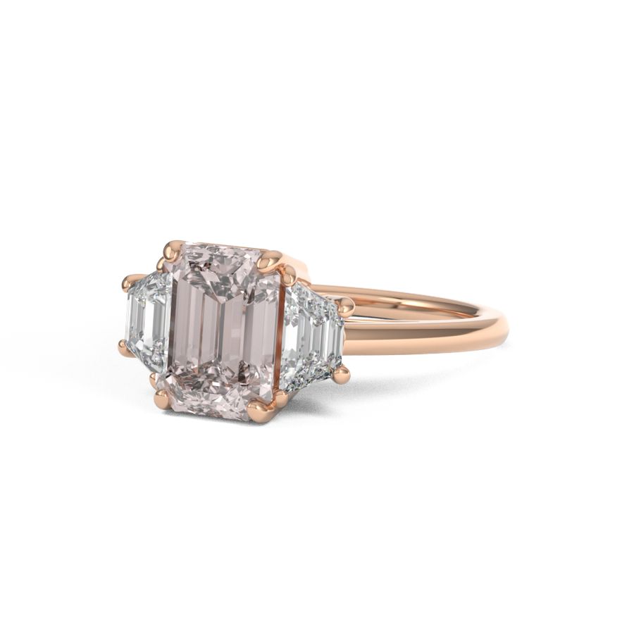rose gold three stone trilogy engagement ring with emerald cut centre and trapezoid side stones