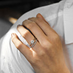 White gold round solitaire engagement ring with diamond wedding ring on a woman with a white shirt