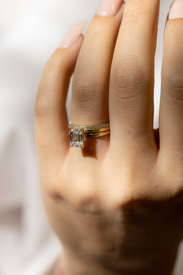 half diamond flat wedding band with emerald cut solitaire engagement ring 