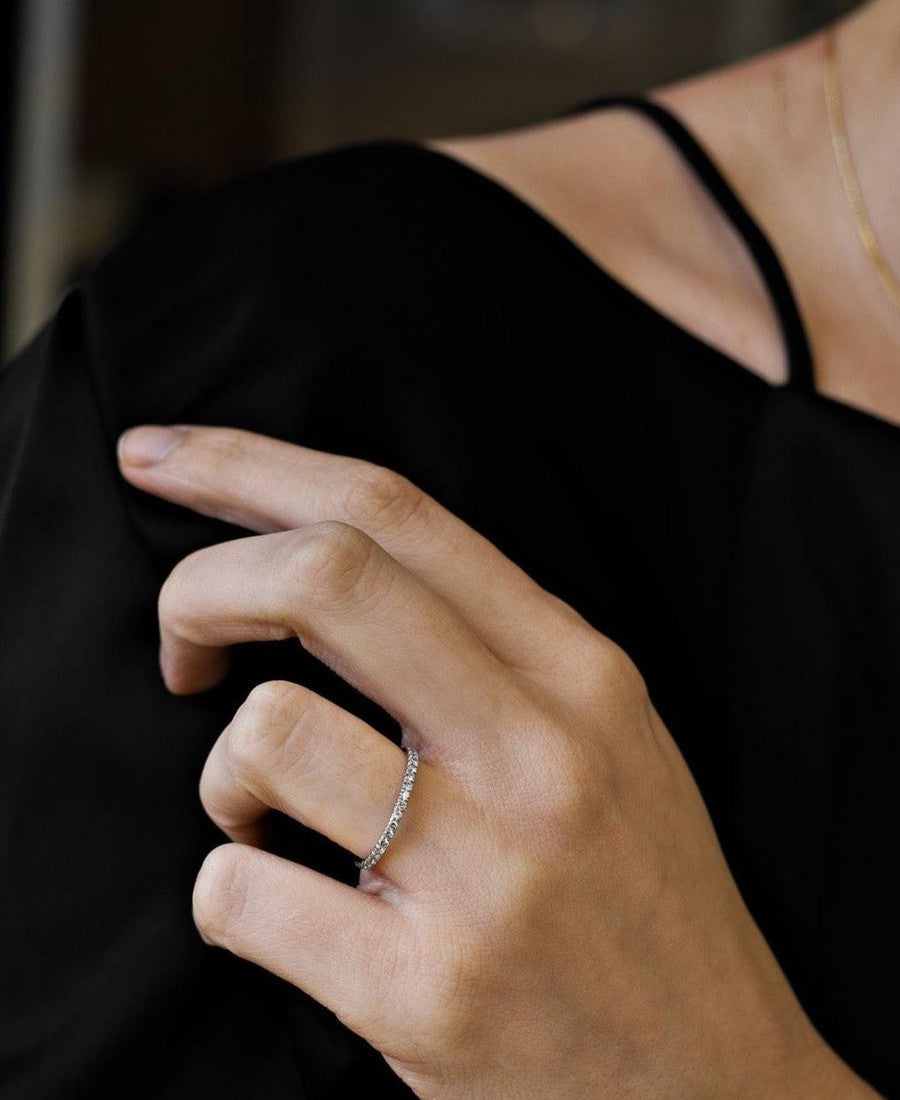woman wearing white gold diamond ring against a black top