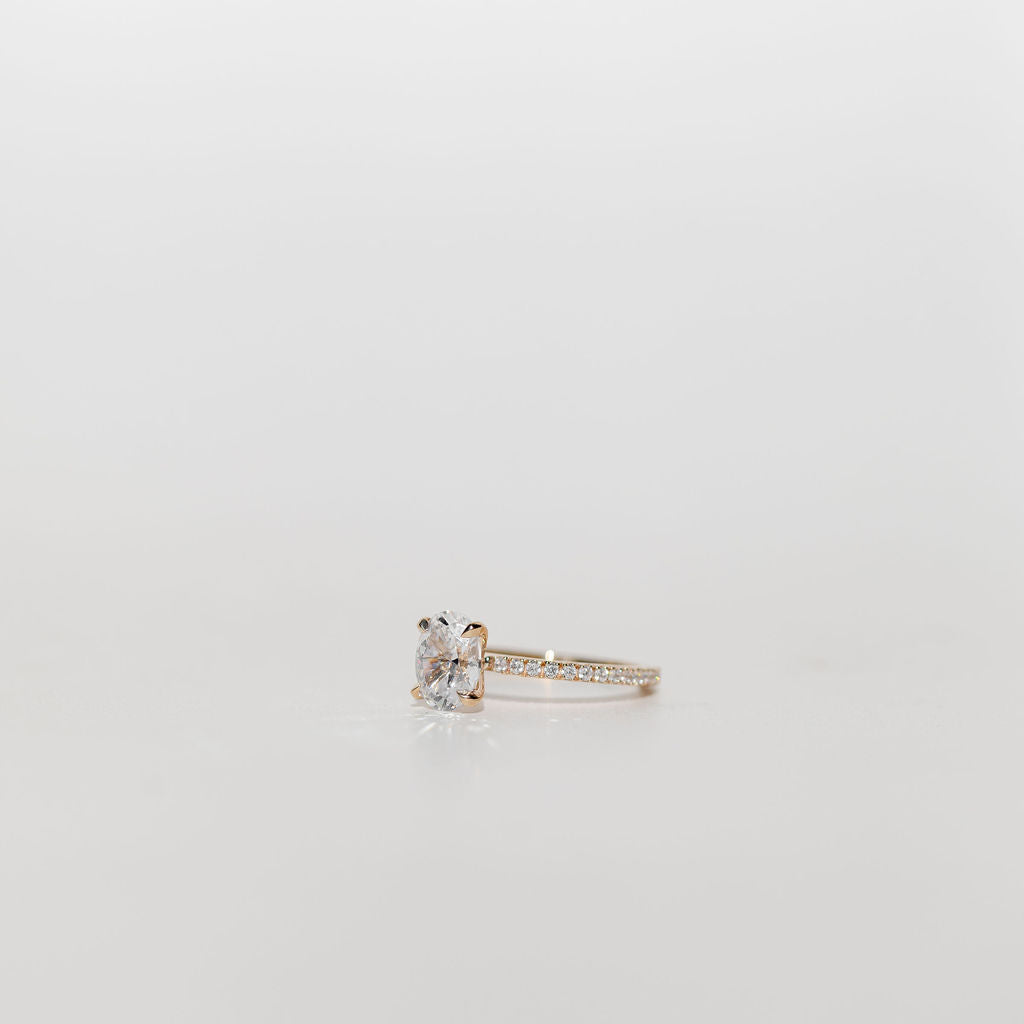 oval diamond cut engagement ring with pave set diamond band in yellow gold