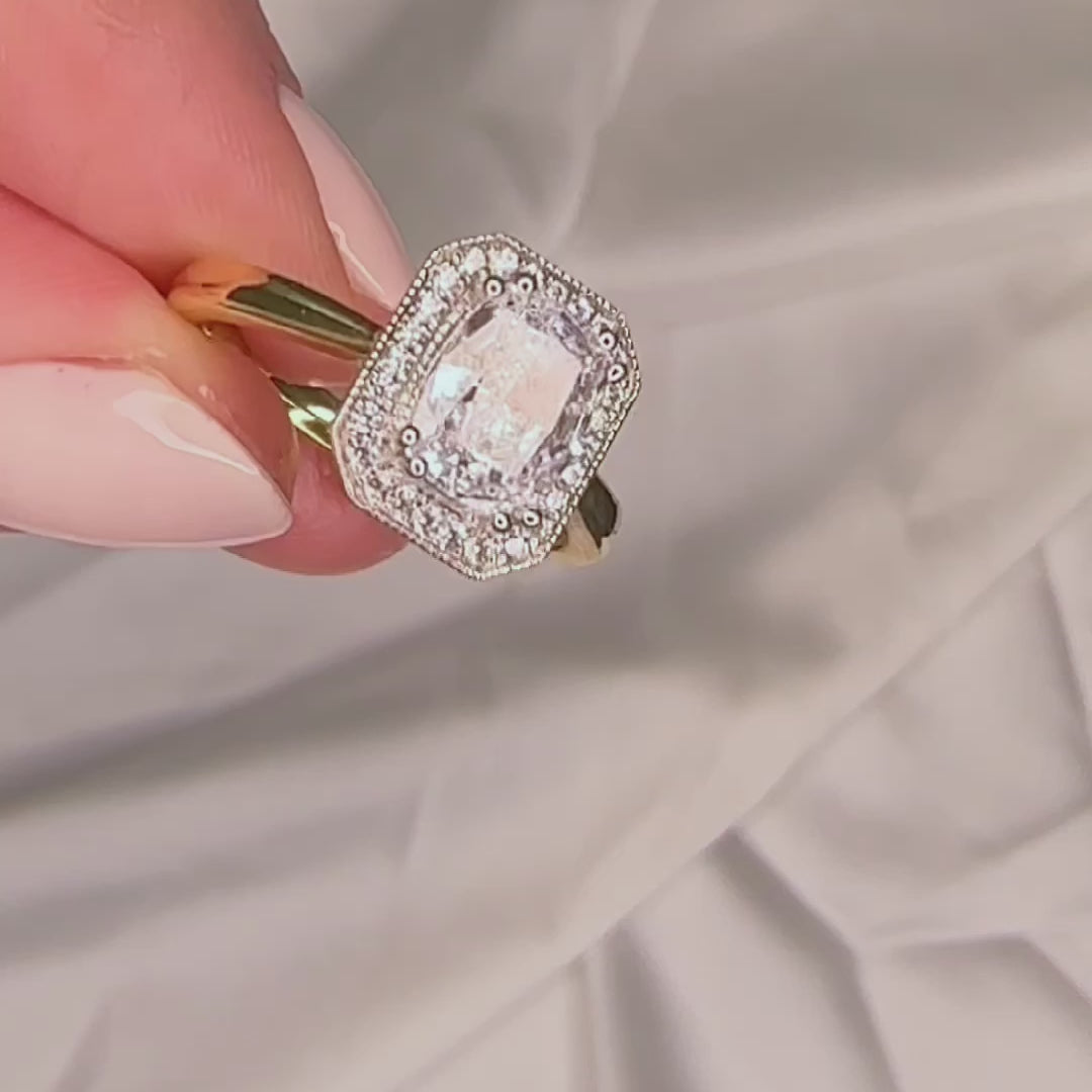 Elongated cushion cut engagement ring with a halo and millgrain detail