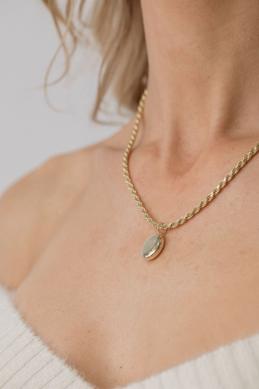 model wearing gold oval locket with rope chain necklace