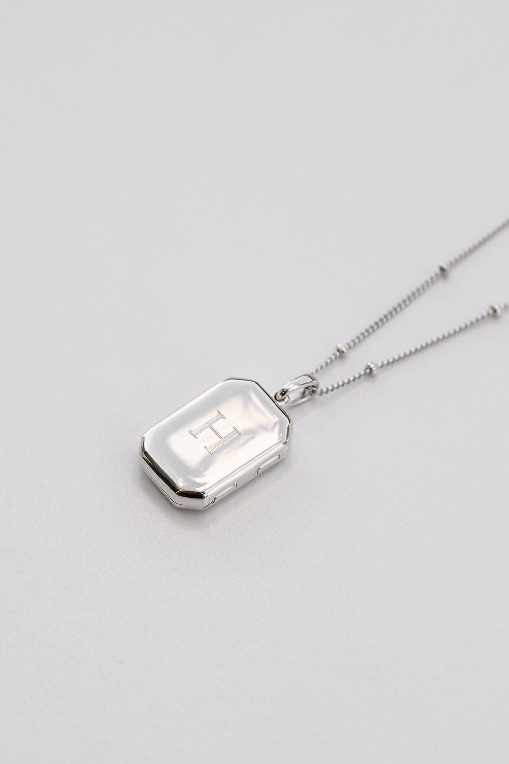 silver rectangular bevel locket engraved with a bead chain necklace